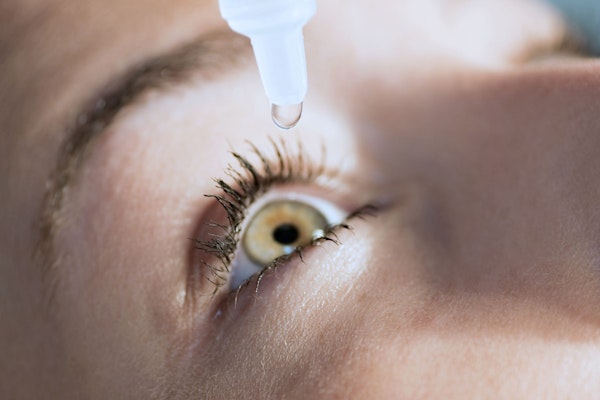Woman putting eye drops into one eye