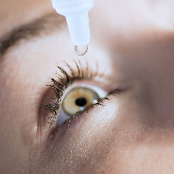 Woman putting eye drops into one eye