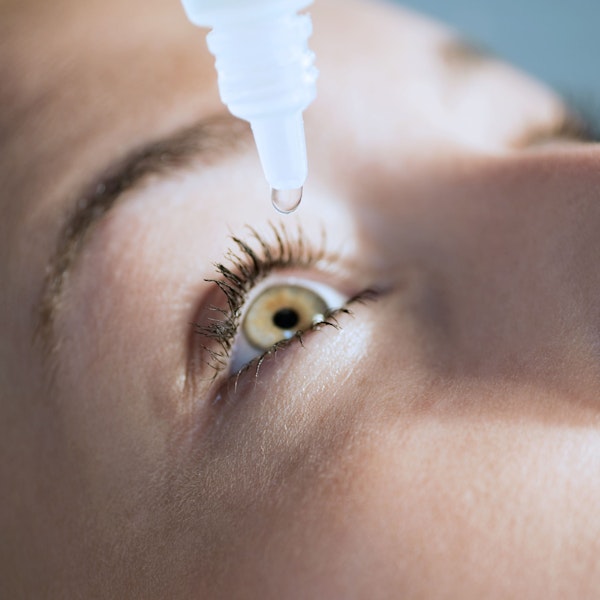 Woman putting eye drops into eye