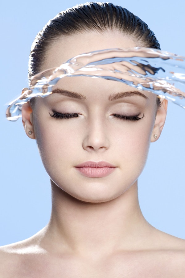 woman with water splashing in front of her face