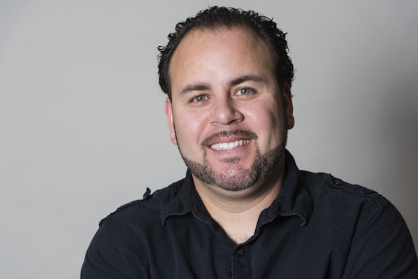 Photo of a man in a black shirt smiling