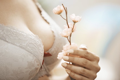 Woman holding flower in front of lacy bra