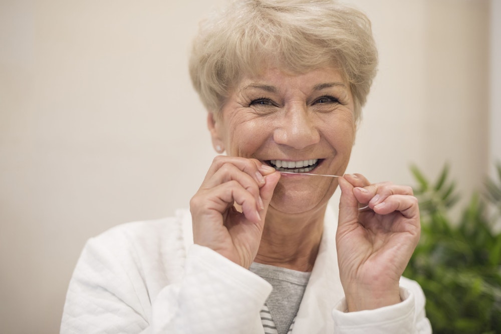 Mature woman flossing teeth
