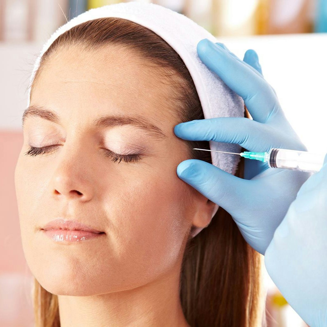 a woman receiving a BOTOX injection in her temple