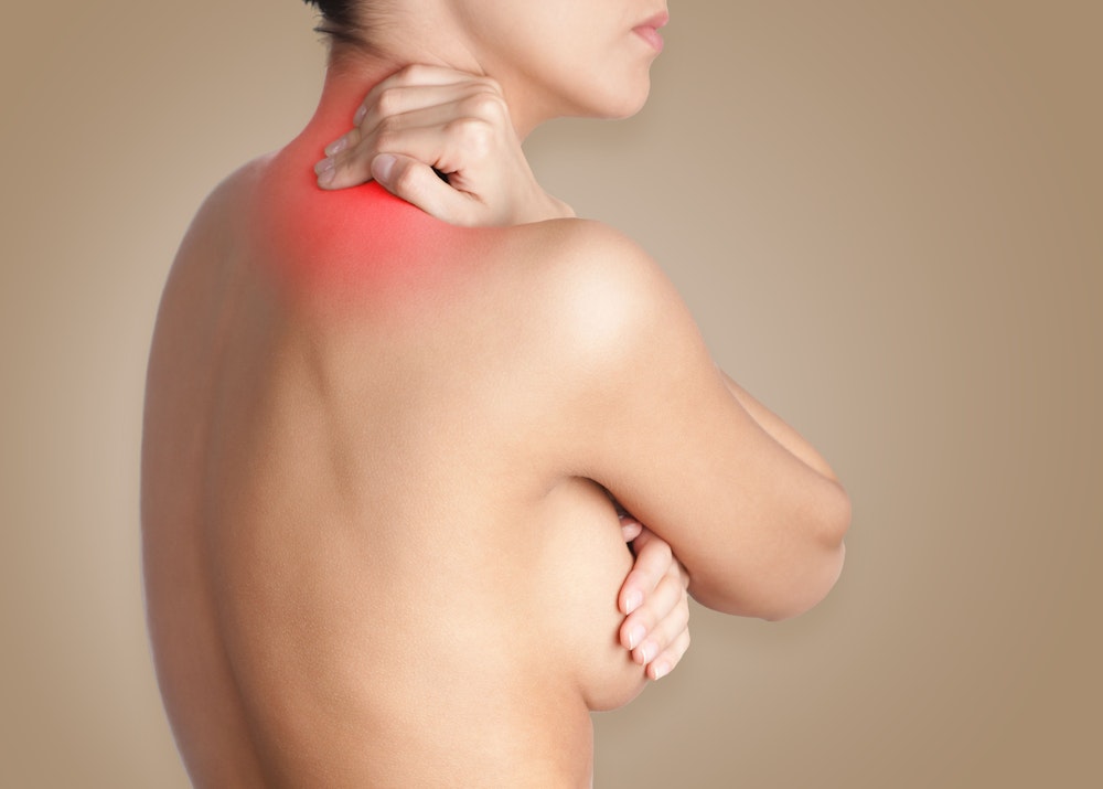 Woman holding neck in pain and covering breast