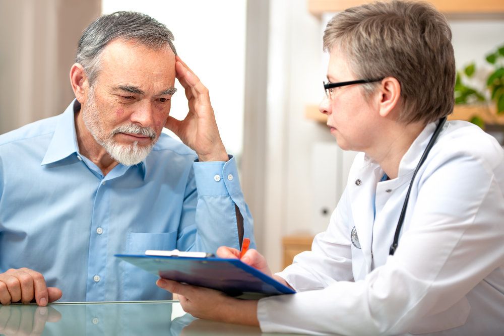 Pensive looking man reviewing paperwork with his doctor