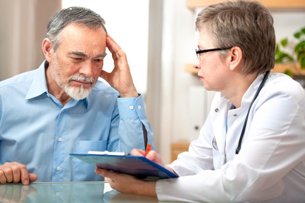Pensive looking man reviewing paperwork with his doctor