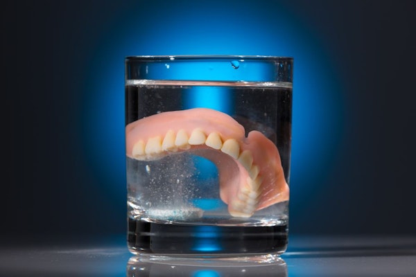 Dentures in glass of cleaning fluid