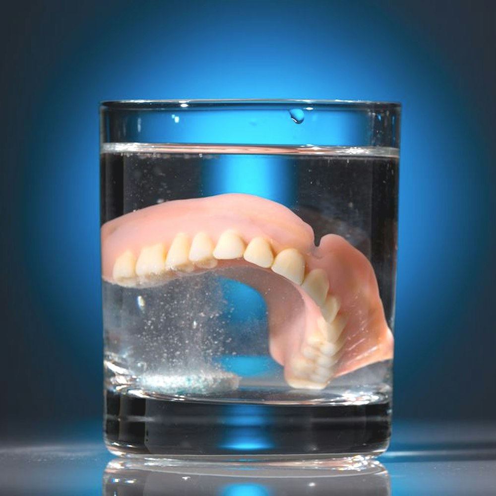 Dentures in glass of cleaning solution
