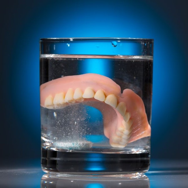 Dentures in glass of cleaning fluid