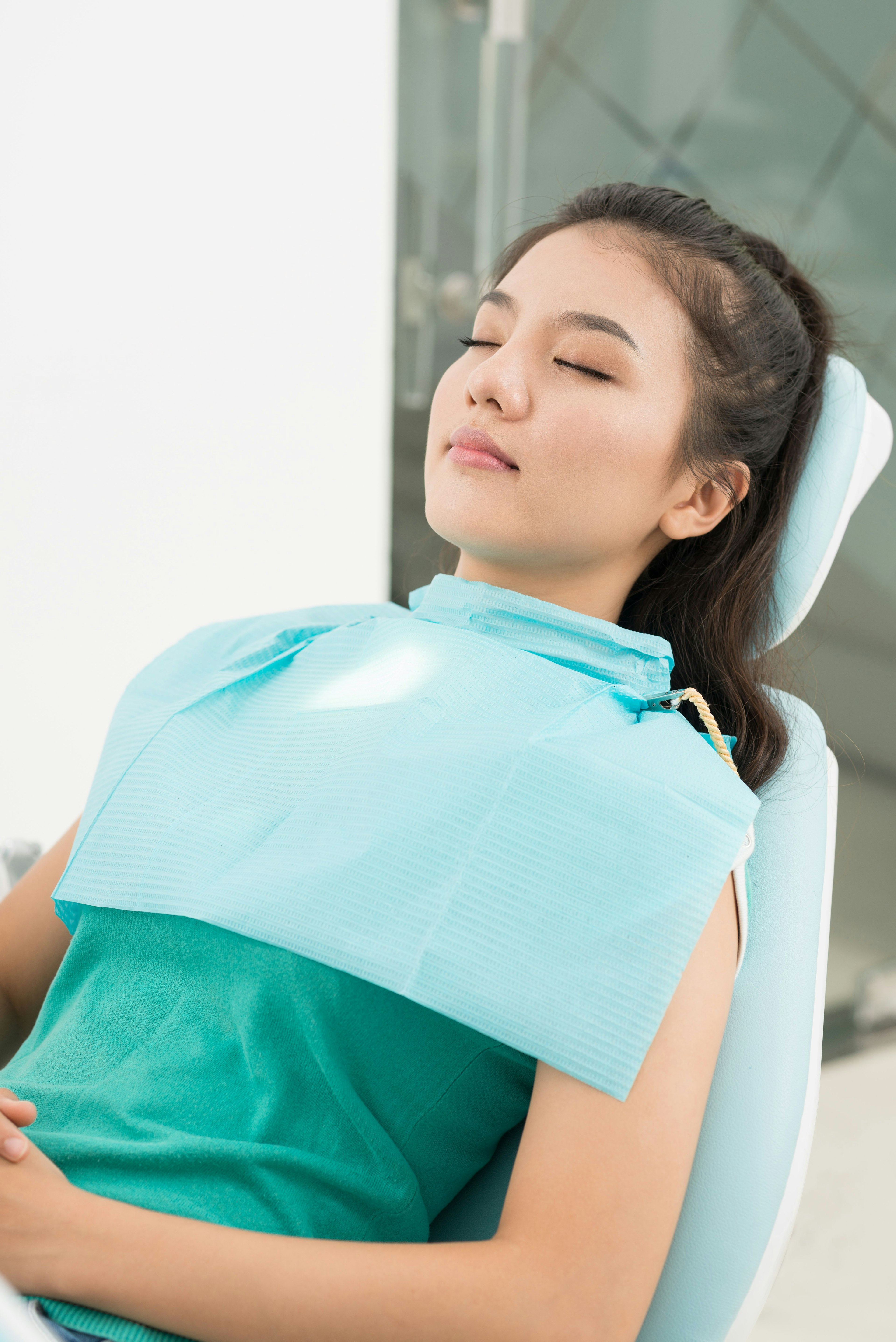 Woman in dental chair with eyes closed
