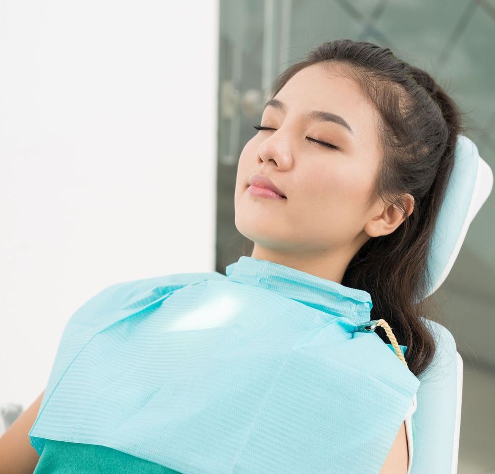 Woman in dental chair with eyes closed
