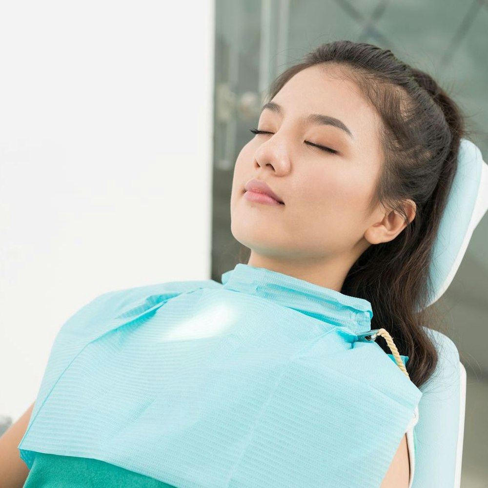 Woman in dental chair with eyes closed