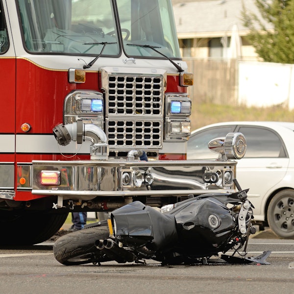 Motorcycle after a car accident with a fire truck in the background