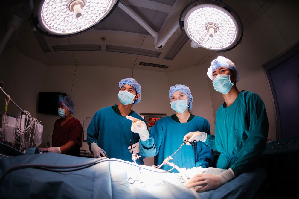 Three doctors performing laparoscopic surgery