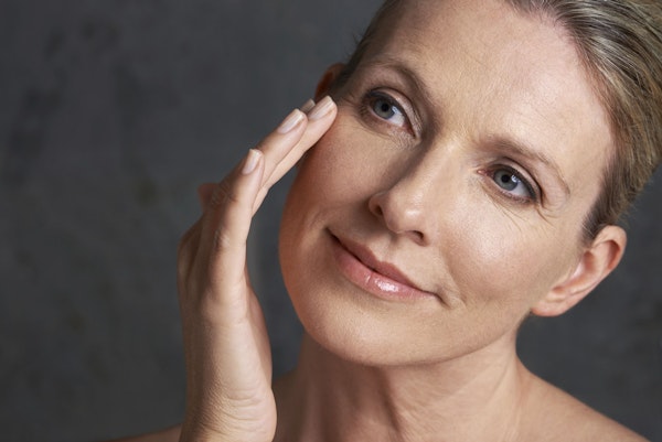 woman holds hand to cheek