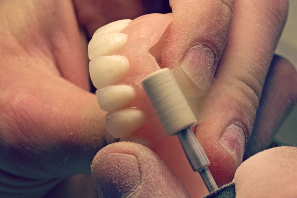 A lab technician crafting a custom denture.