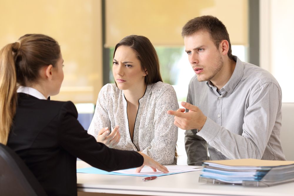 Couple facing lawyer from across desk