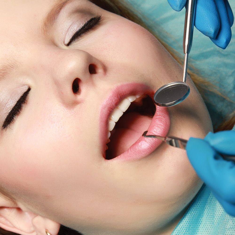 Unconscious woman having her teeth inspected