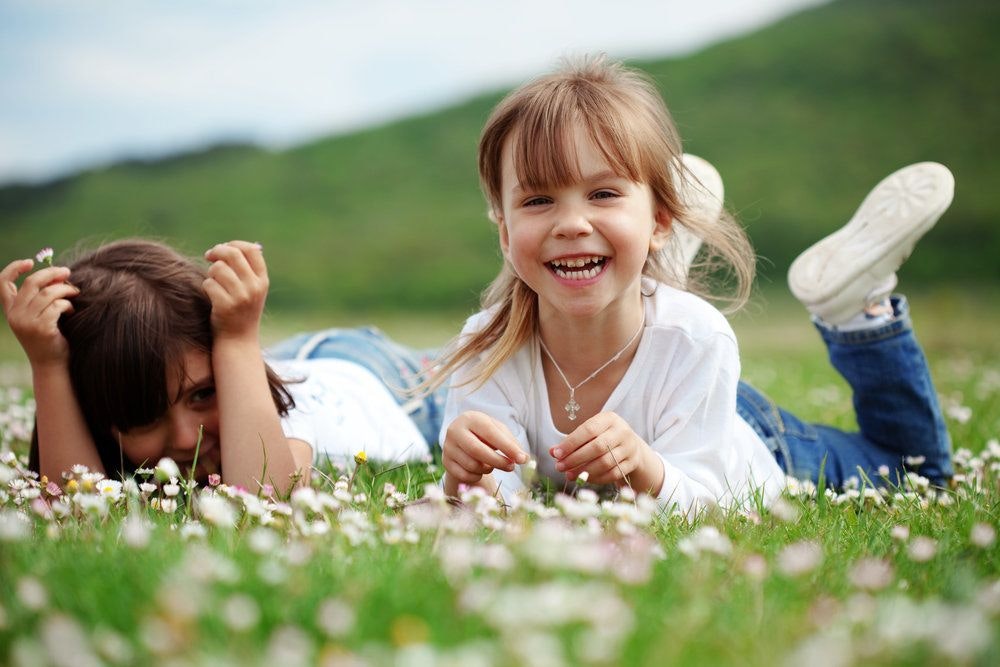 Girl smiling and laying with friend in field of flowers