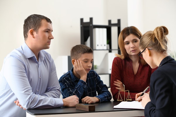 Couple with child sitting across desk from lawyer