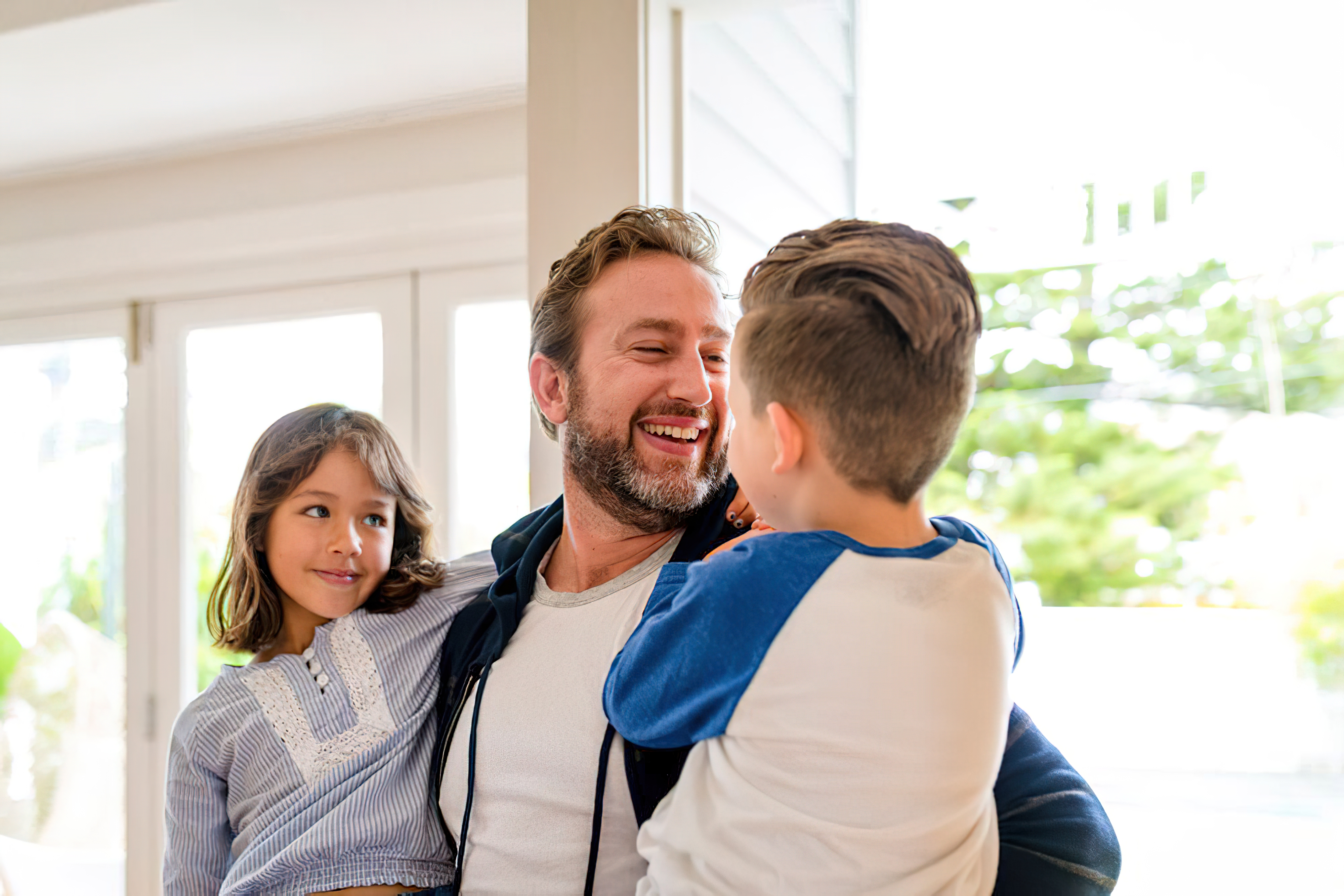 Laughing father holding two young children