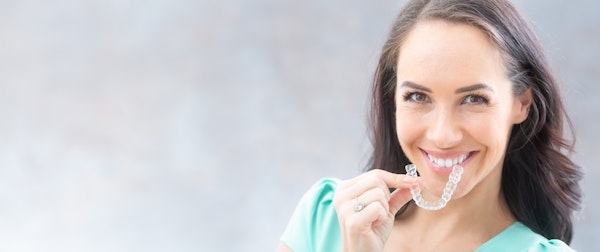 Woman holding invisalign close to her mouth