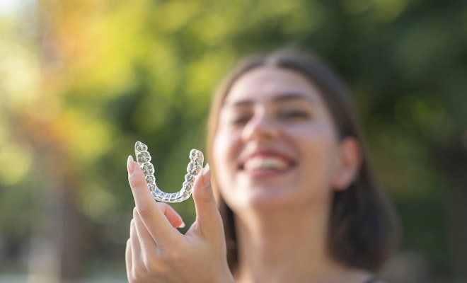 Smiling woman holding invisalign