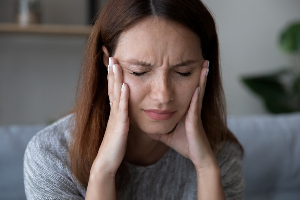 Woman holding both sides of jaw in pain