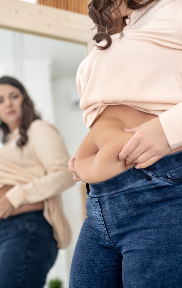 Woman looking at stomach in mirror