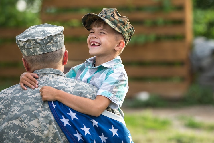 Son laughing while holding military father