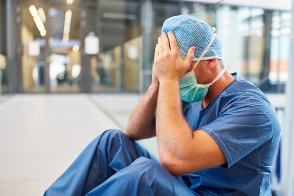 Stressed hospital employee with head in hands
