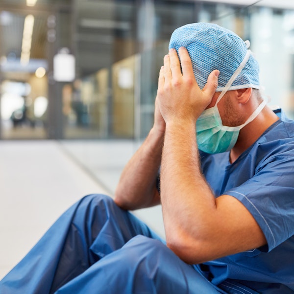 Stressed hospital employee with head in hands
