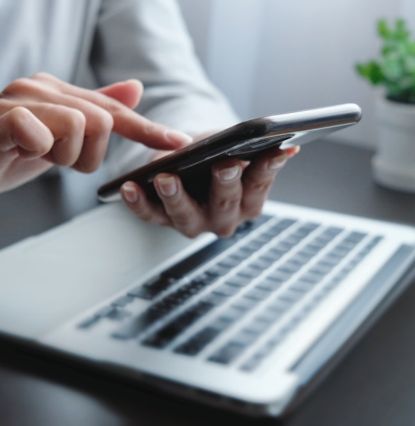 Person scrolling through phone and computer