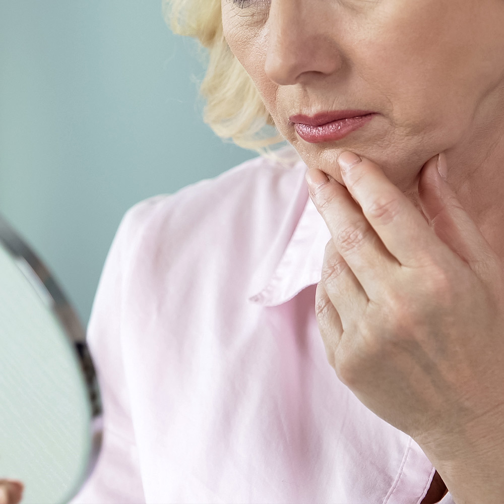 Woman looking at wrinkles in mirror
