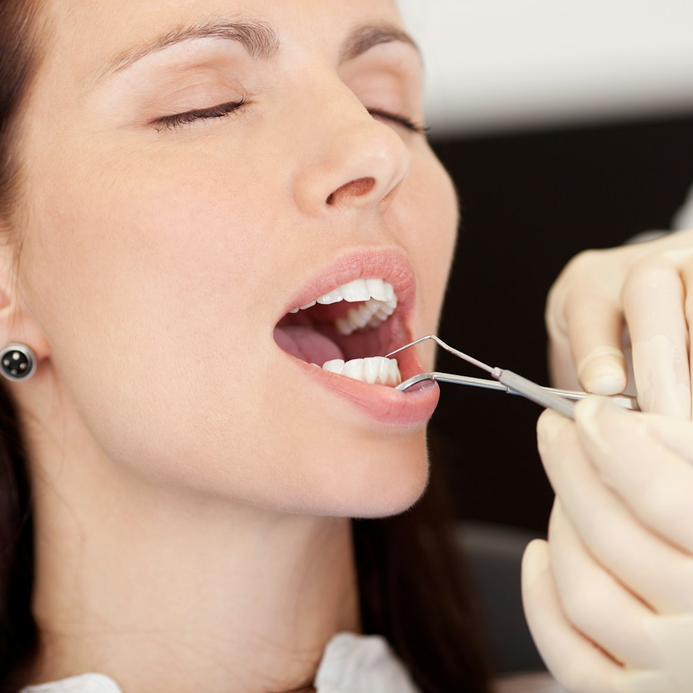 Sedated woman with dental tools in her mouth
