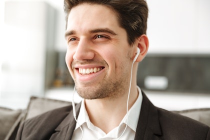 A young man smiling with earphones in