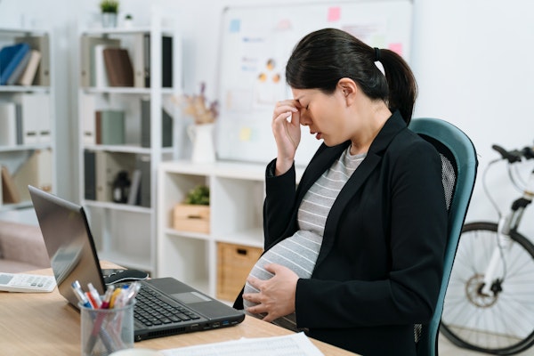Stressed pregnant woman at work