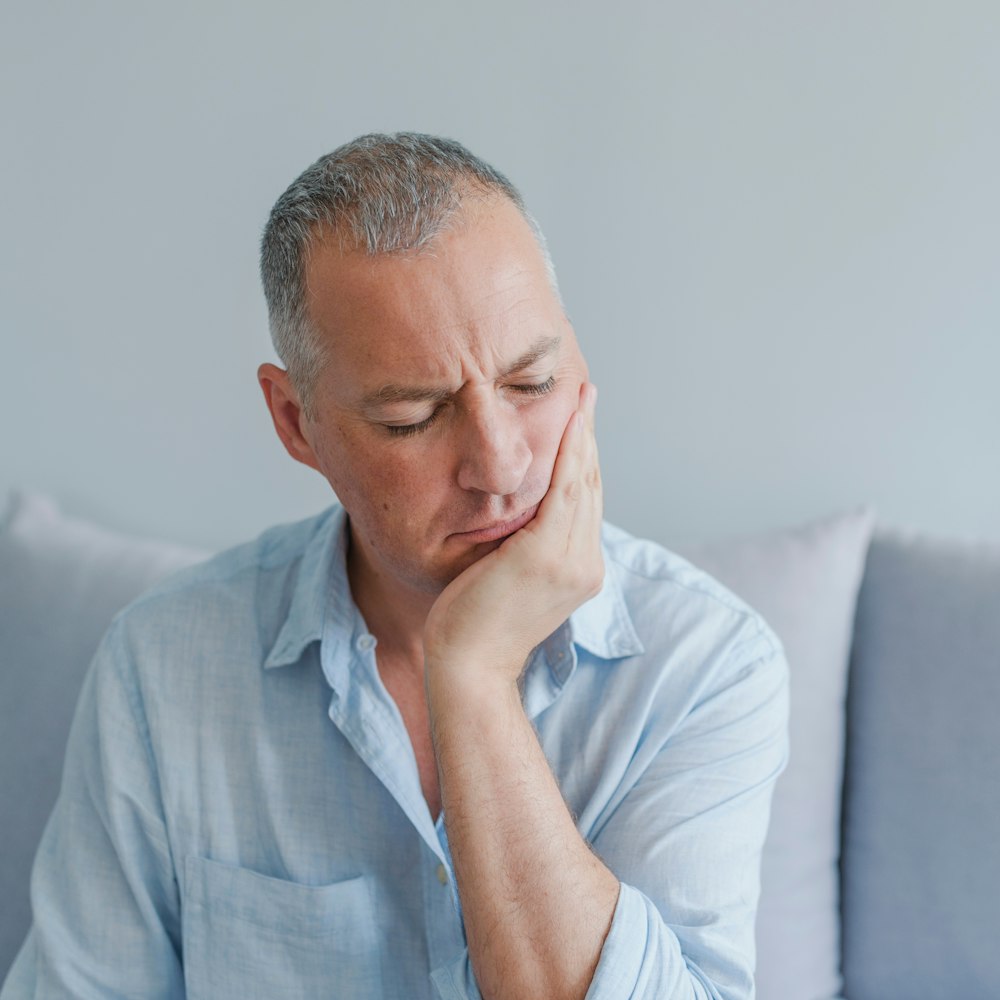 Man holding side of mouth and in need of periodontal care
