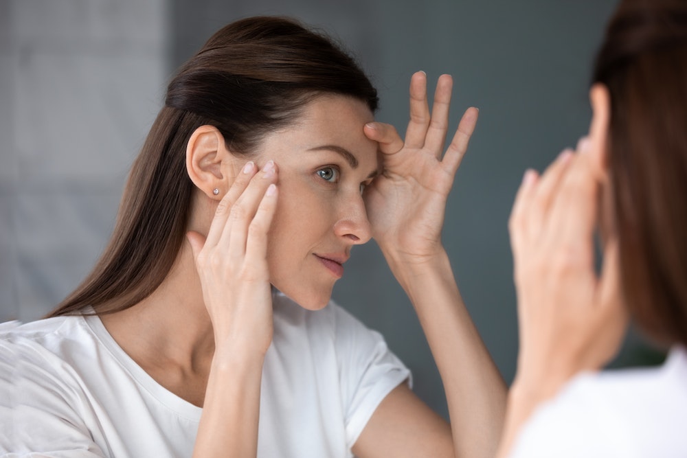 woman examining face in mirror
