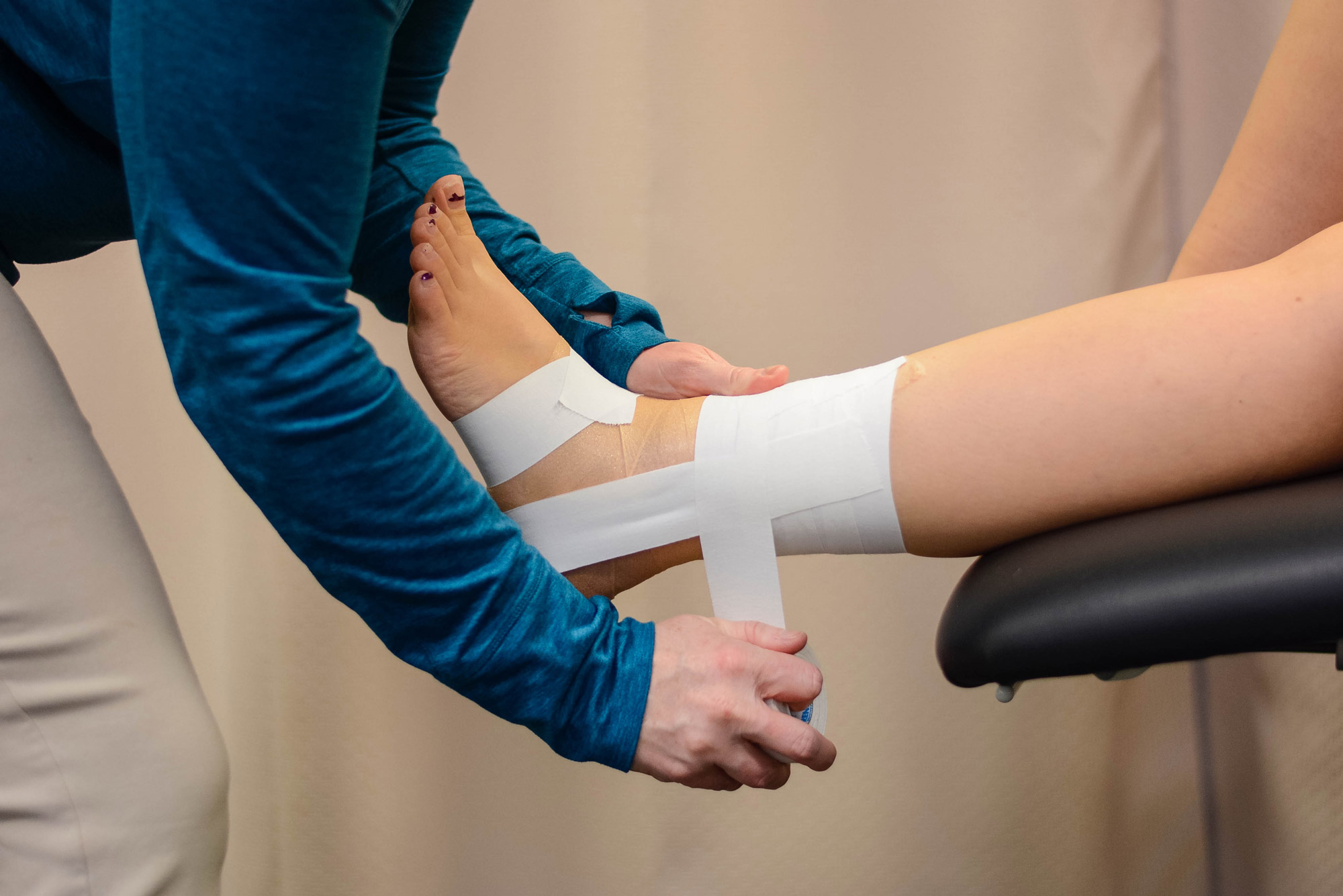 Doctor wrapping ankle with tape