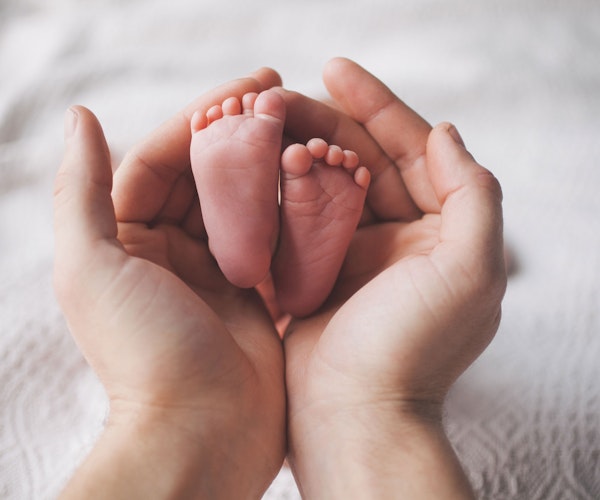 Adult holding baby's feet in hands