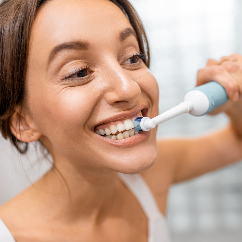 Woman brushing teeth with an electric toothbrush