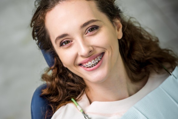 smiling woman wearing clear braces outdoors