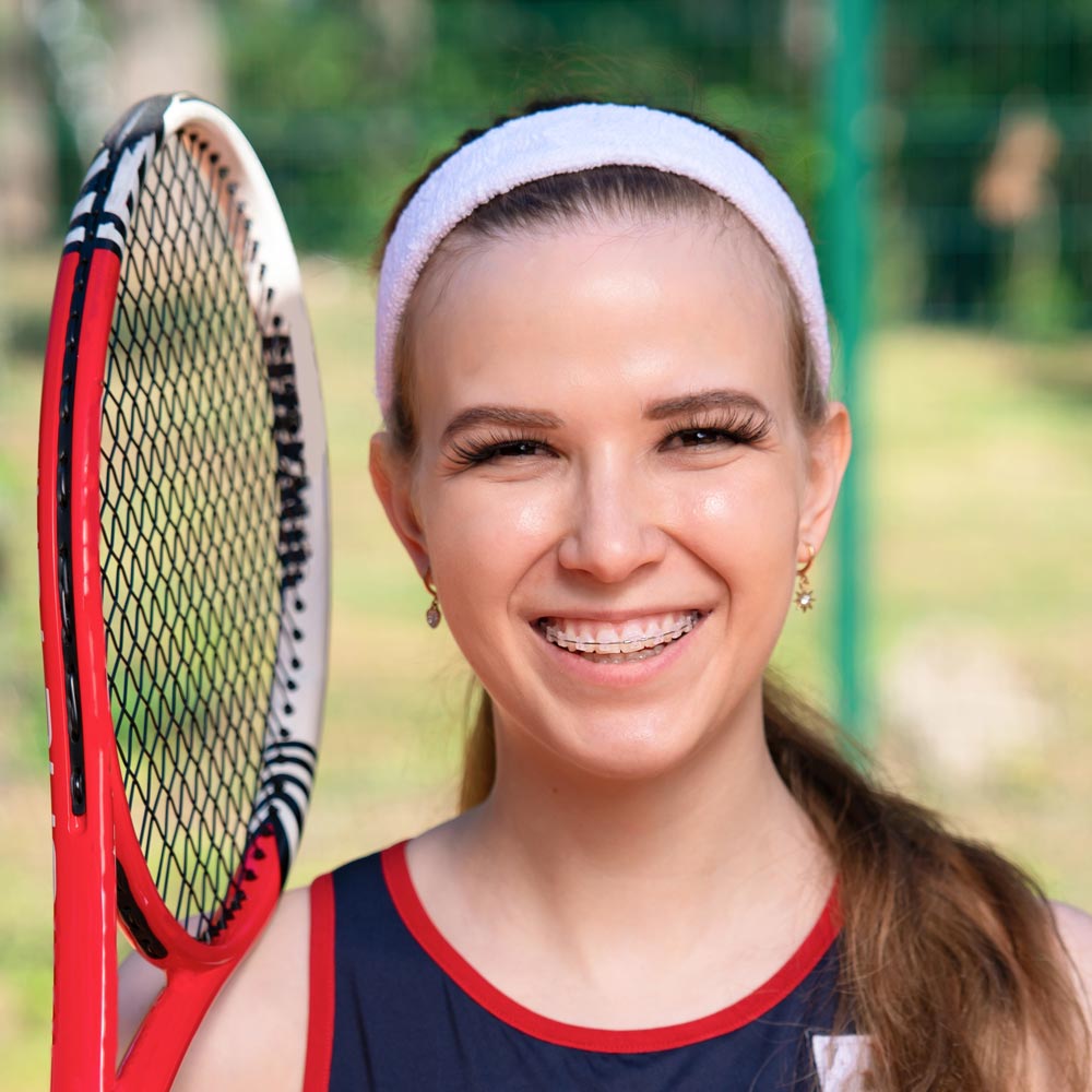 Teenager holding tennis racquet and wearing clear braces