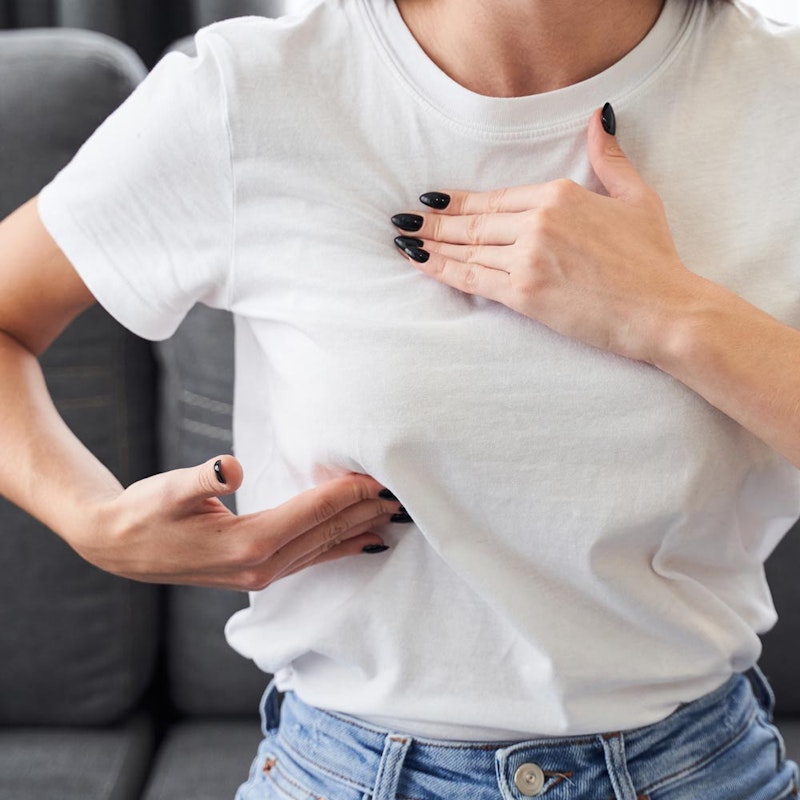 Woman gingerly touching chest