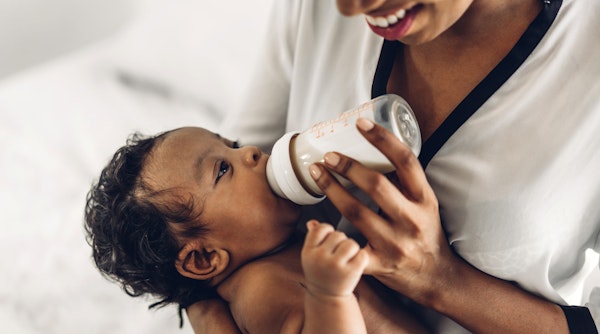 Young mom feeding newborn baby with bottle milk