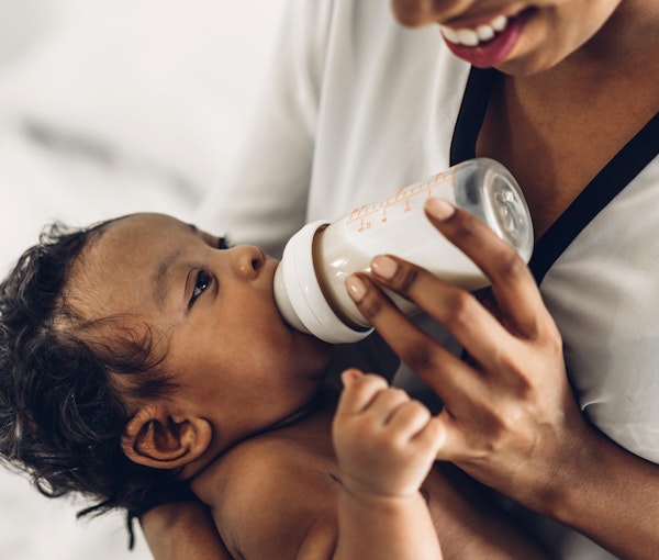 Young mom feeding newborn baby with bottle milk