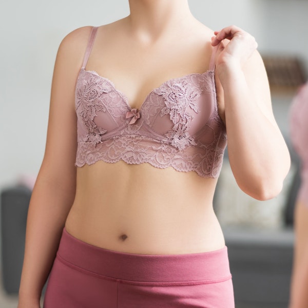 Woman in pink bra and yoga pants looking into the mirror