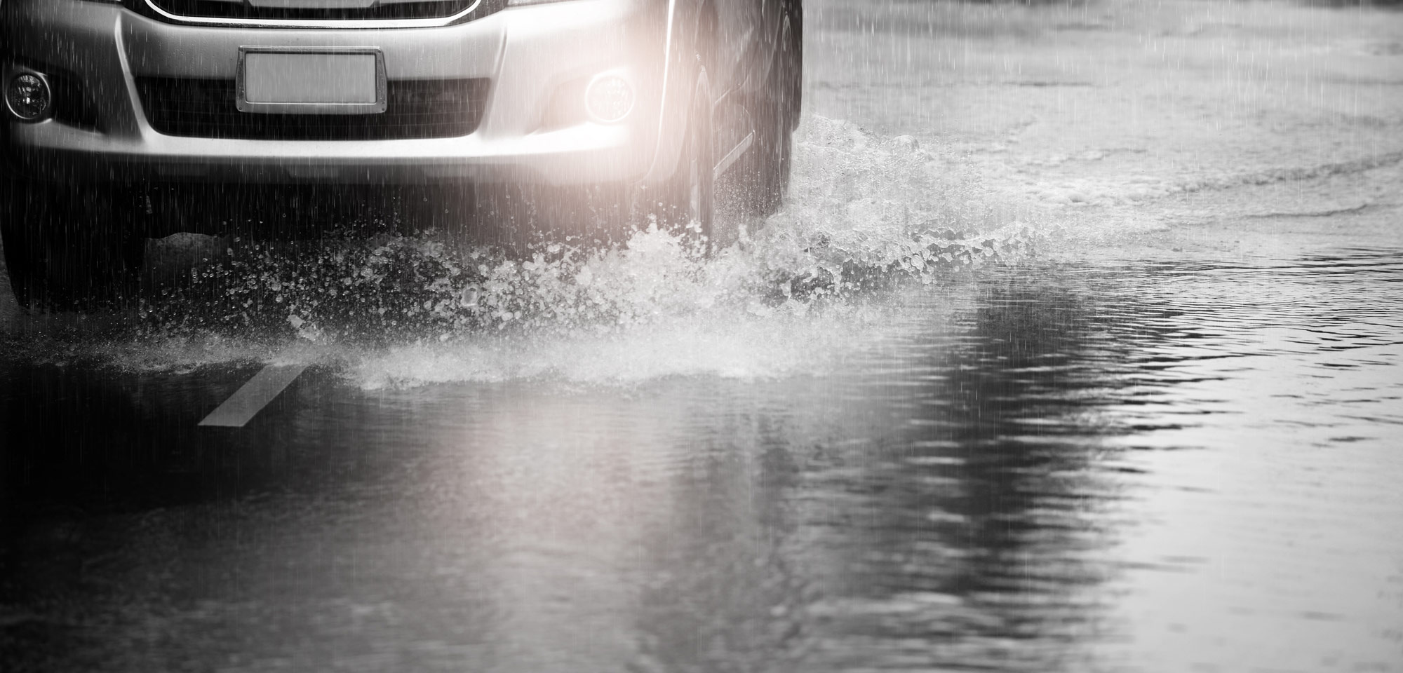 car driving through deep puddle in heavy rain
